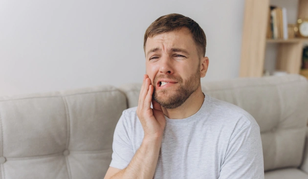 Man holding cheek in pain